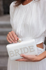 Bring your bridal celebrations wherever you go with Shiraleah's "Bride" Pearl Minaudiere. This classic white purse features the word "Bride" embroidered in chic faux pearls with a faux pearl top closure. You can carry it like a clutch or use the detachable cross-body chain for some extra versatilaty in your style. Pair with other items from Shiraleah's Hitched collection to complete your look!
