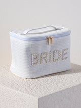A rectangular cosmetic pouch with a top handle and a zip top opening, embroidered with the word "Bride" in faux pearls