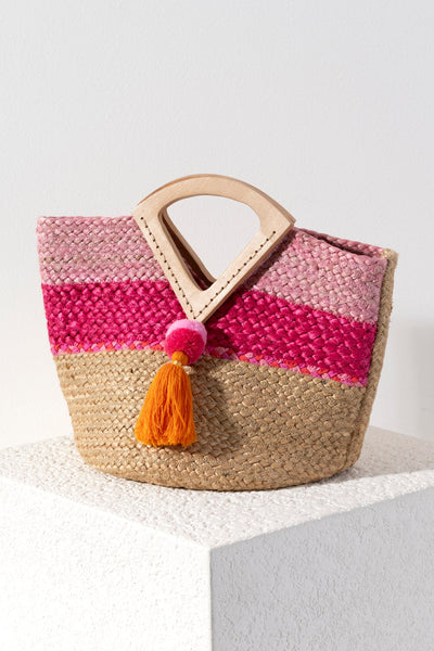 Bring some brightness to your summer accessories with Shiraleah's Rola Mini Tote. Made from woven jute and featuring chic triangular double handles, it is the perfect bag to bring to the beach or to the bar. The multicolor pink stripe pattern and pom tassle detail adds a playfulness to any outfit. Pair with other items from Shiraleah to complete your look!
