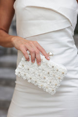 Bring blooming flowers along wherever you go with Shiraleah's Fiorella Minaudiere. This elegant white purse is decorated with flower & rhinestone embellishments with a classic faux pearl top clasp. You can carry it like a clutch or use the detachable cross-body chain for some extra versatility in your style. Pair with other items from Shiraleah to complete your look!
